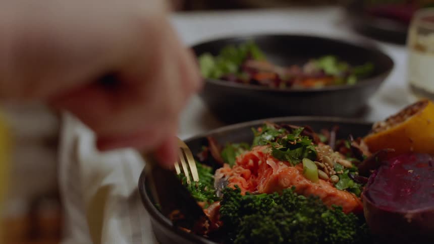 A white woman cuts into her meal while her spouse talks to her over the table