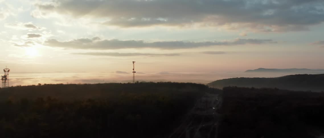 Cars sit parked near the rural countryside at dusk