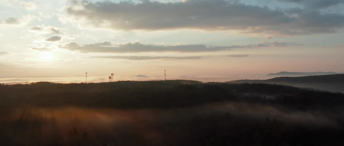 The sun sets over a hilly landscape