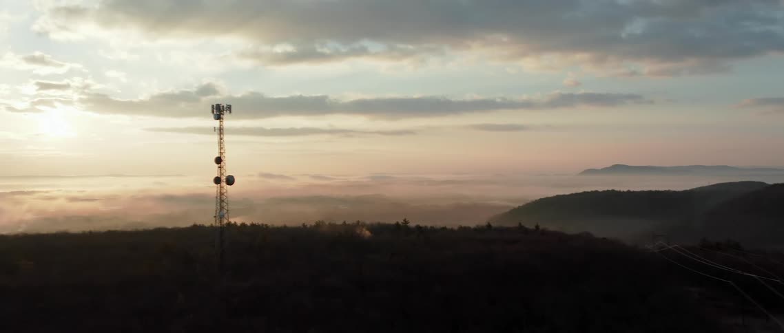 An antenna sits in nature near mountains and a valley