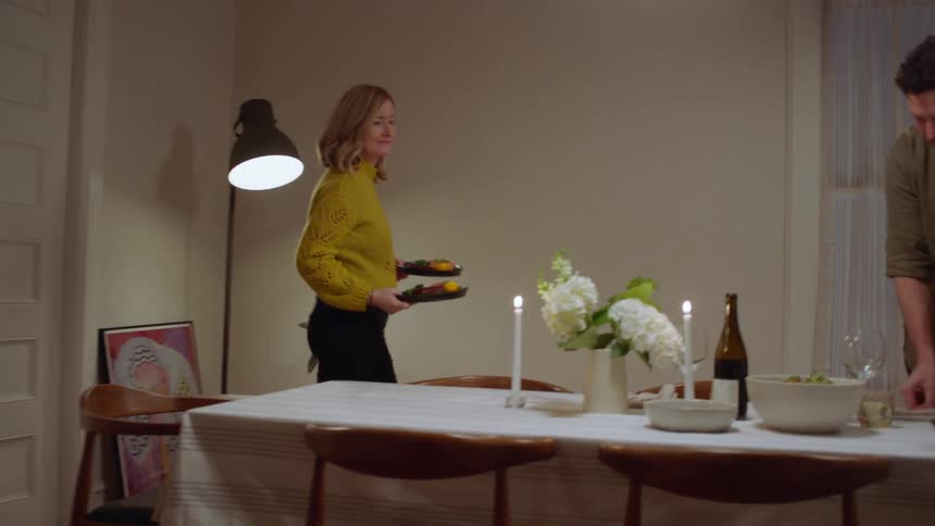 A white couple prepare to eat dinner at a dining room table