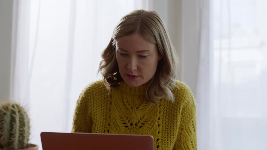 A woman sitting down typing on a laptop