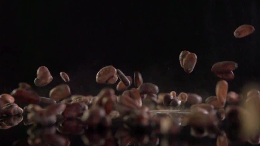 Coffee beans falling on a sheet of glass