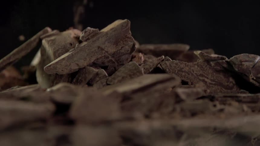 Pieces of various sizes falls onto pile against dark background