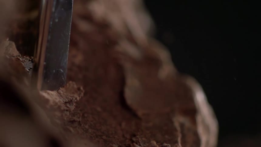 A sliver of chocolate is chiseled from a larger chunk