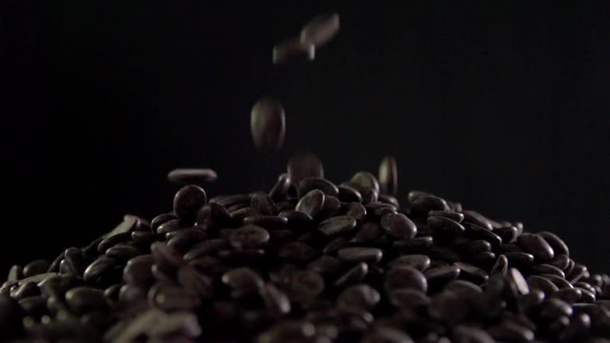 Whole coffee beans are poured in a mound