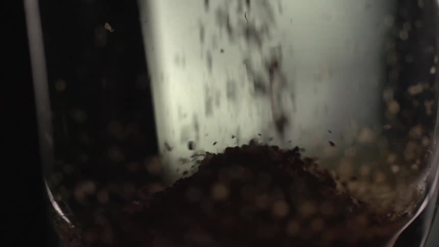 Ground coffee spills into glass