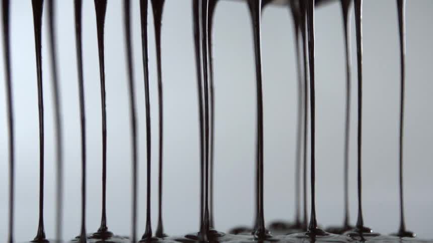 Long strings of chocolate drip from a plastic mold