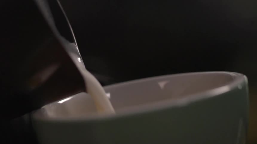 Cream is poured into a white coffee mug