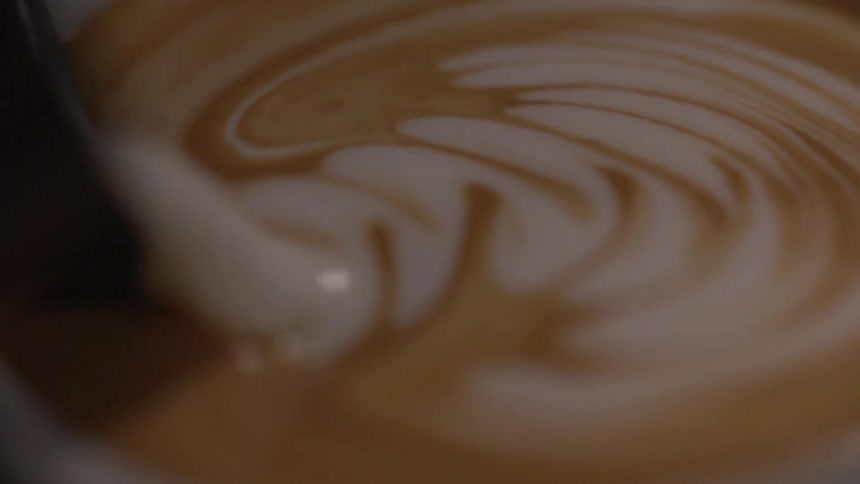 Pouring swirl design onto top of latte