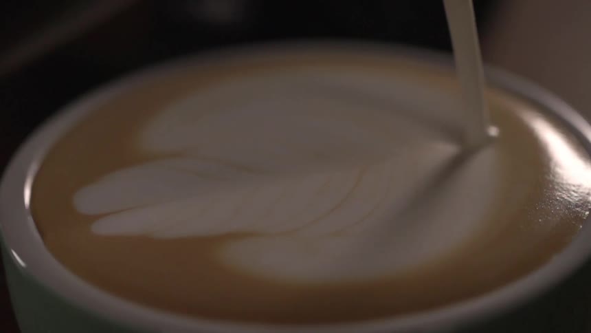 Milk being poured in a mug of latte