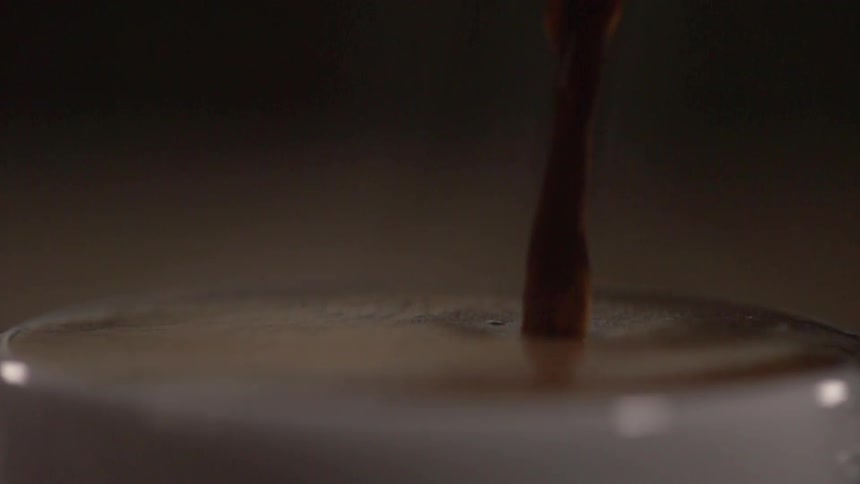 Chocolate pours into a glass filled with liquid