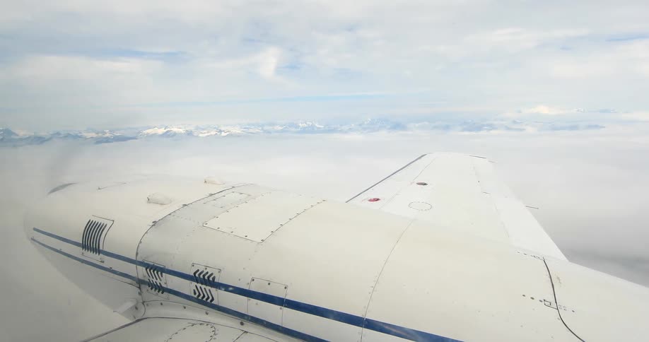 An airplane flies near mountains on a cloudy day