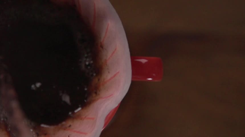 Water pouring into red stoneware mug