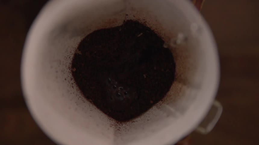Water pouring into container of coffee grounds