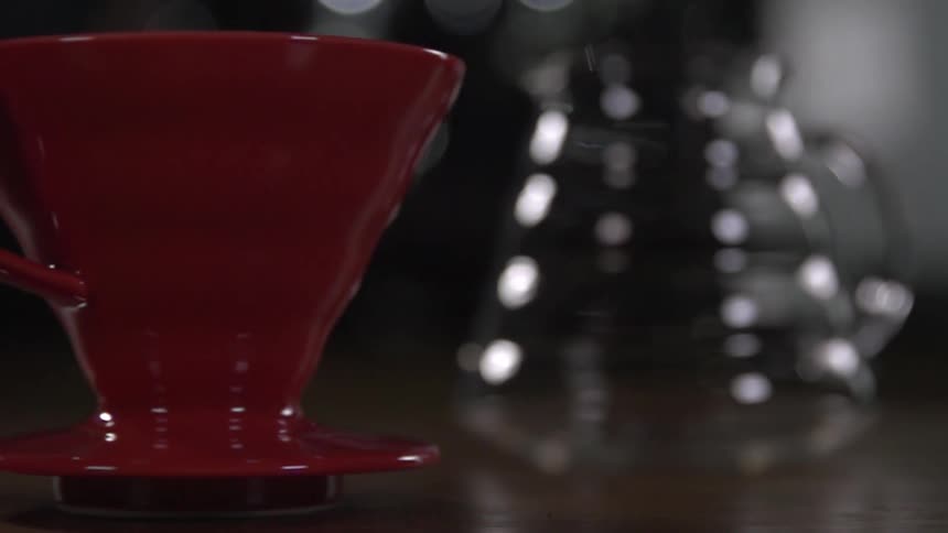 A red coffee cup slides across a table