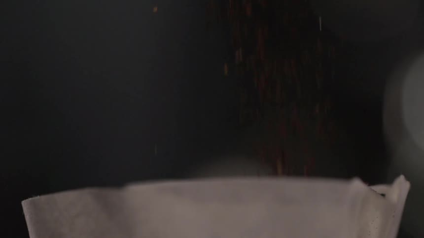 Coffee grinds drop into a paper filter
