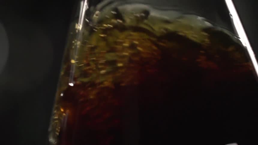 Close view of dark brown beverage swirling in glass