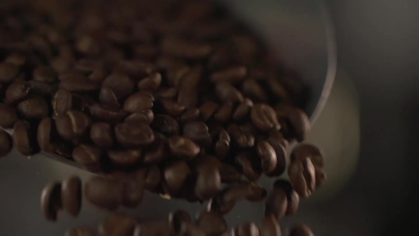 Coffee beans being poured out of a scoop