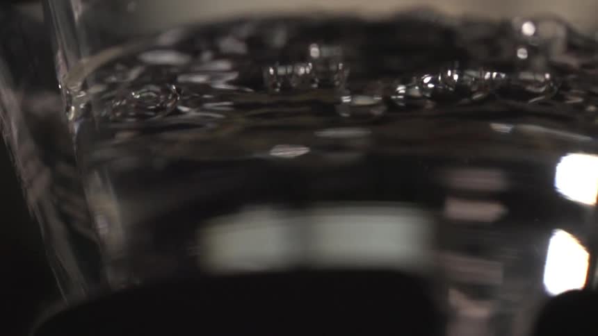 A glass contains a bubbling clear liquid