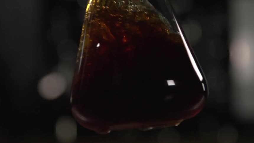 A brown liquid sloshing in a glass flask