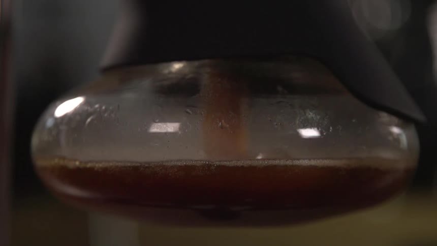 A dark brown liquid fills a glass container