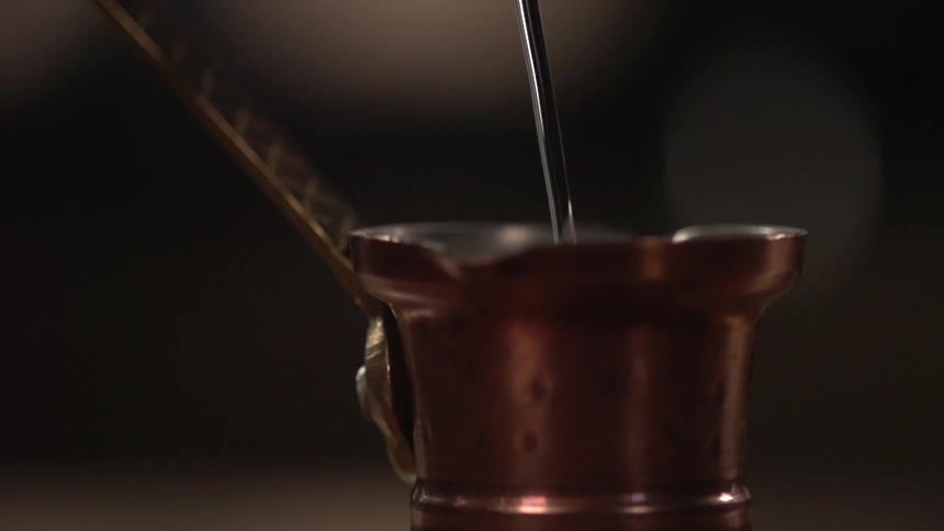 Water pouring into a copper carafe for brewing