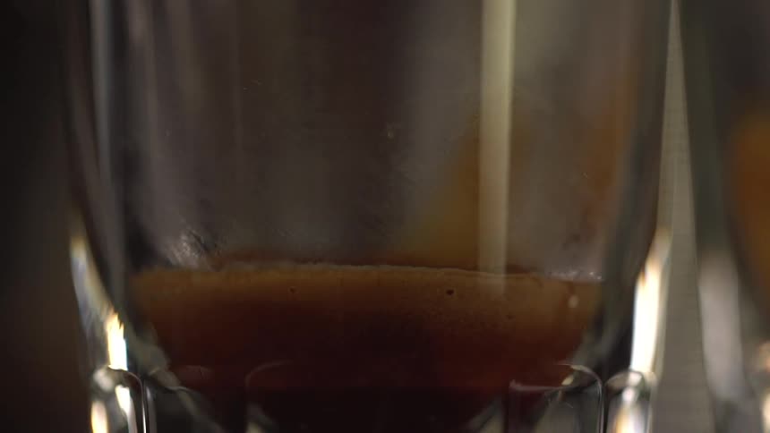 Brown liquid is poured into a glass