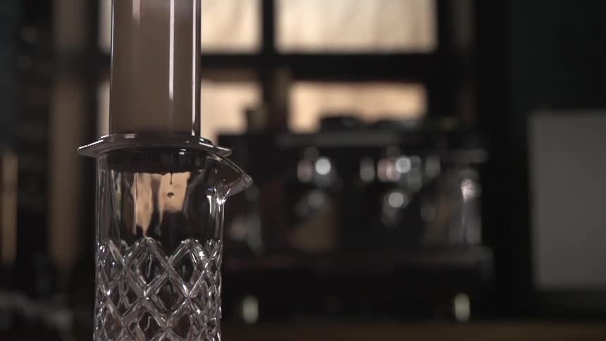 Several drops of liquid fall into a glass container