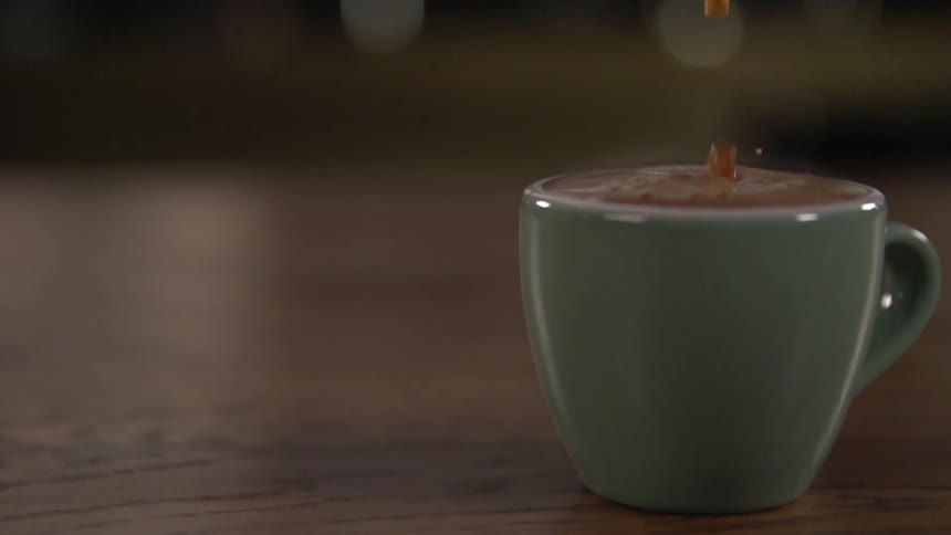 Brown liquid pours into green ceramic cup almost to brim