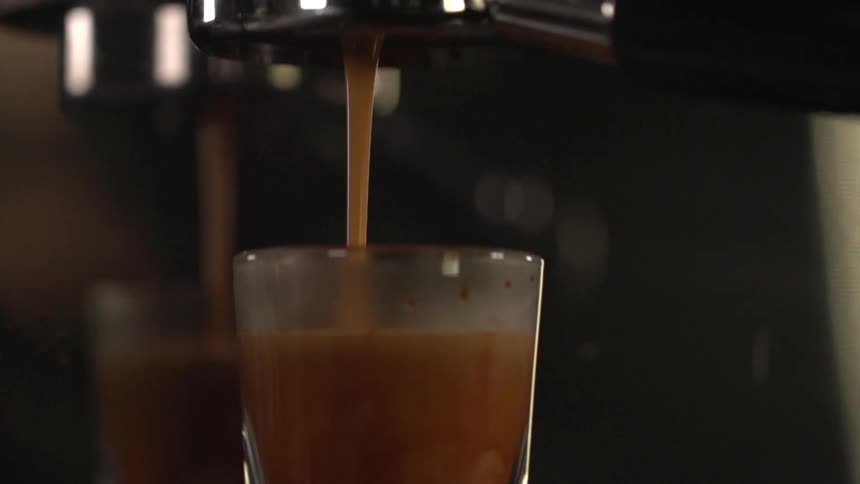 A machine fills a drinking glass with a brown fluid