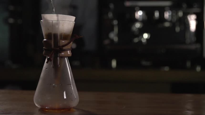 A glass flask filling with liquid sits on a wooden counter