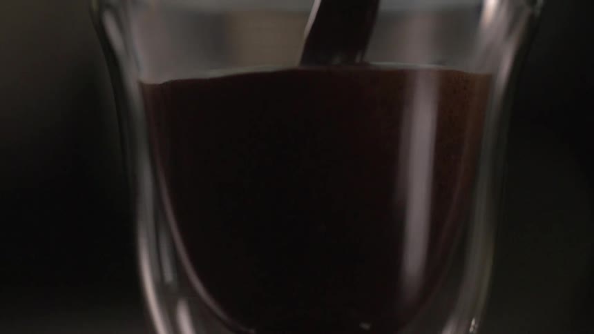 A dark and thick liquid fills a small glass