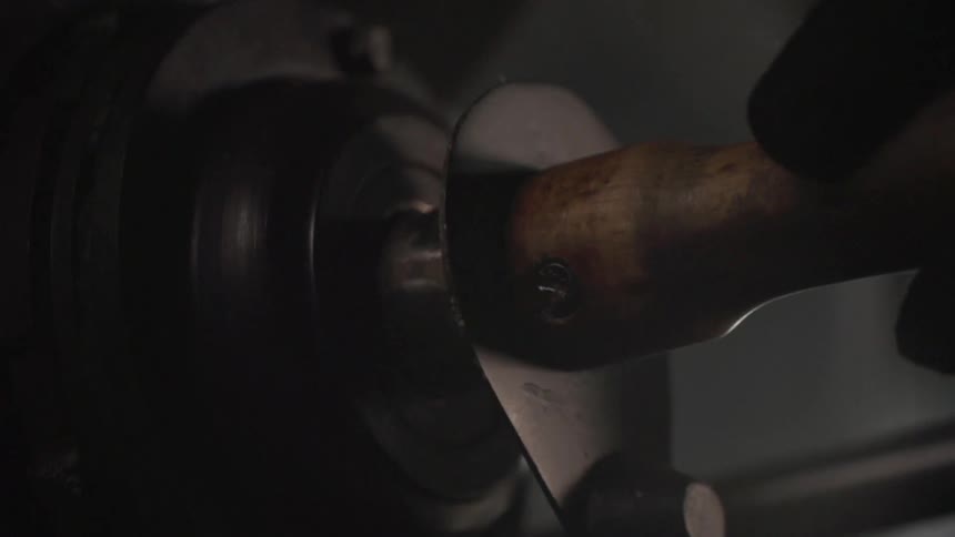 A black gloved hand slides a piece of machinery into a slot
