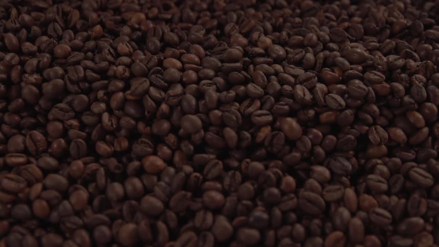 Coffee beans being stirred with metal utensil