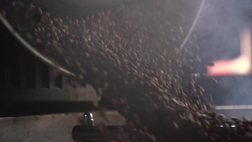 Coffee beans being poured in a roaster in a factory