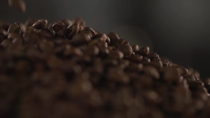Roasted coffee beans are poured into a pile