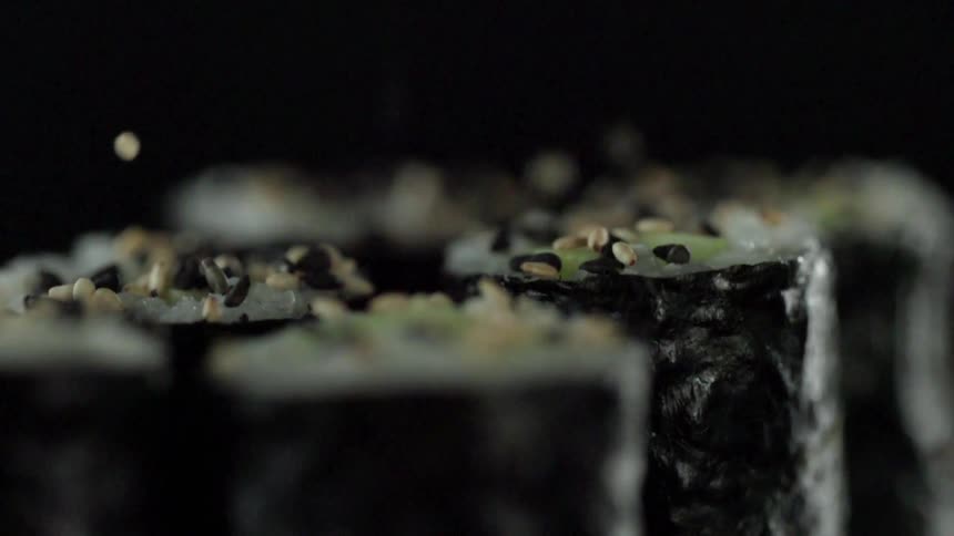 Sesame seeds dropping onto sushi rolls
