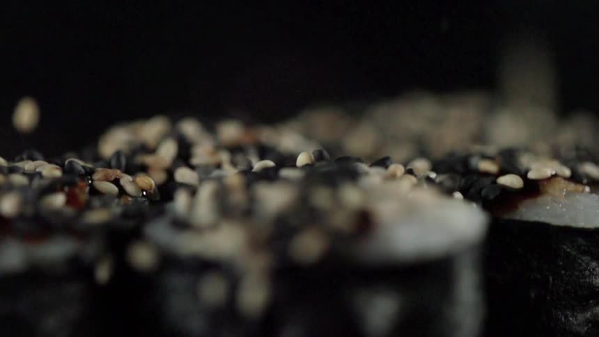 Seeds fall into a pile on a black surface