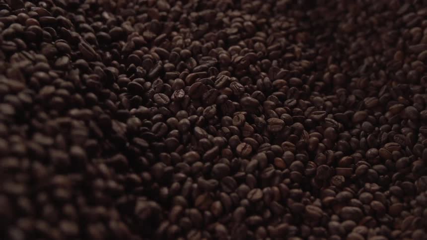 Metal scoop stirs fresh coffee beans