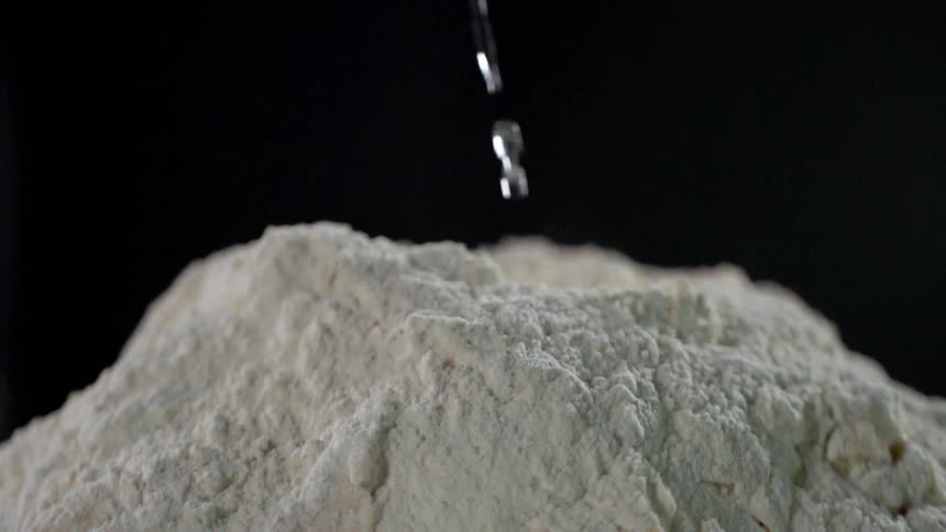 Water being poured over white flour