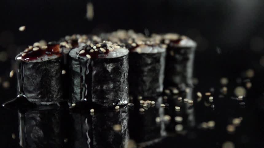 Sesame seeds falling onto fresh sushi rolls