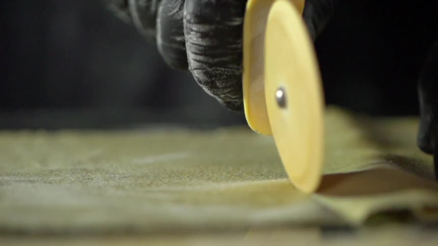 A person is cutting fabric with a rolling cutter