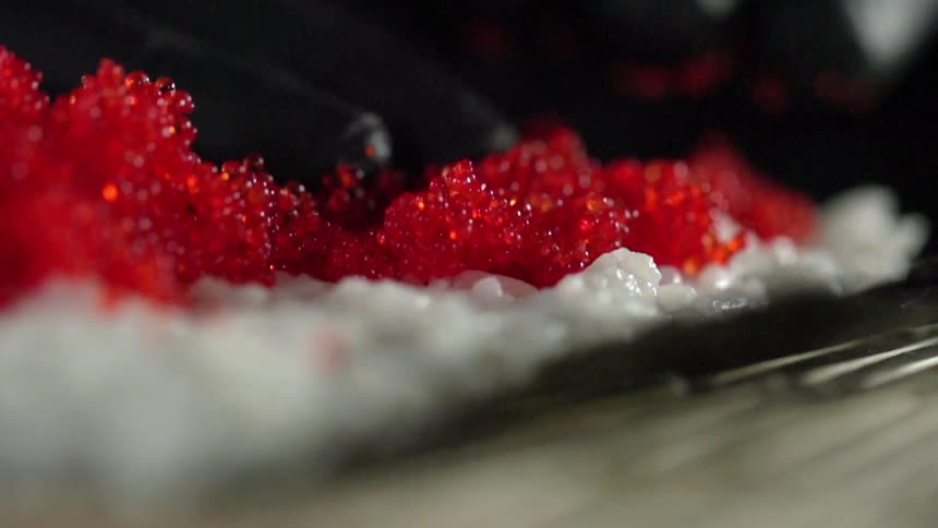 A sushi chef spreads fish roe over rice