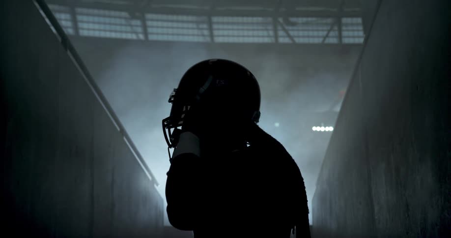 Silhouette of man putting on football helmet