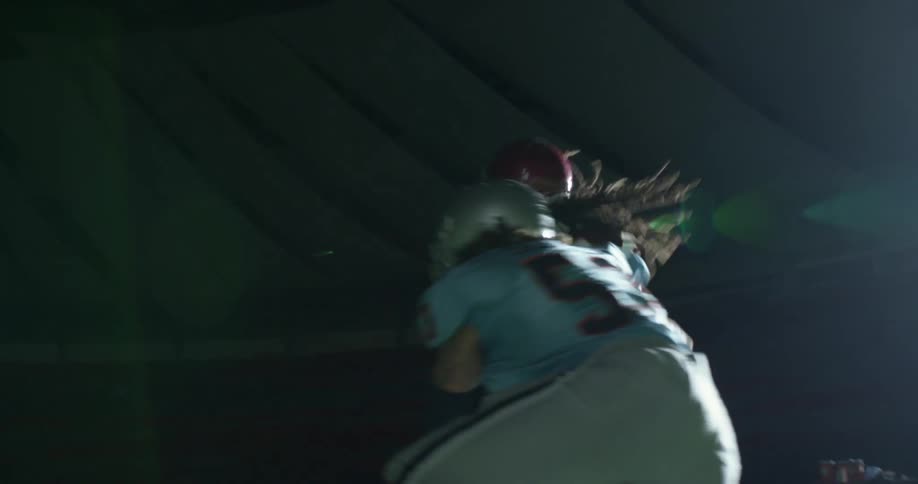 A football player runs with the ball and another player tackles him