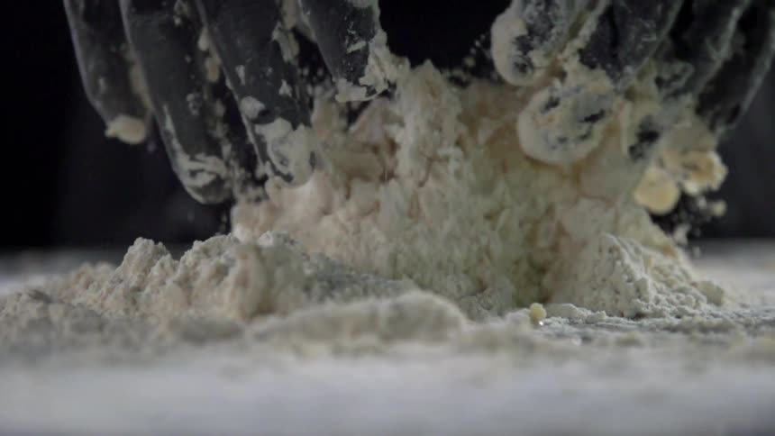 A chef runs his hands through a pile of flour