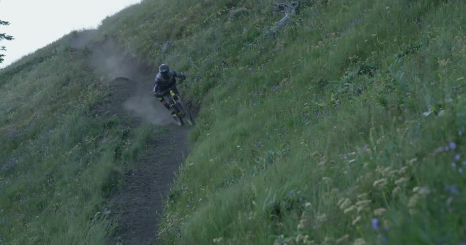 Mountain biker rides down trail on mountainside at dusk 2