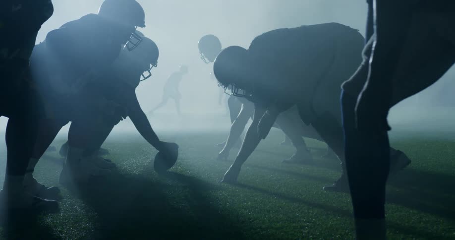Football players playing game in silhouette with fog