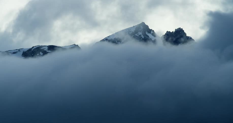 Thick mist flowing across a snowy mountain ridge